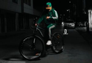 Man in vibrant green outfit rides bike at night in Bogotá's urban setting.